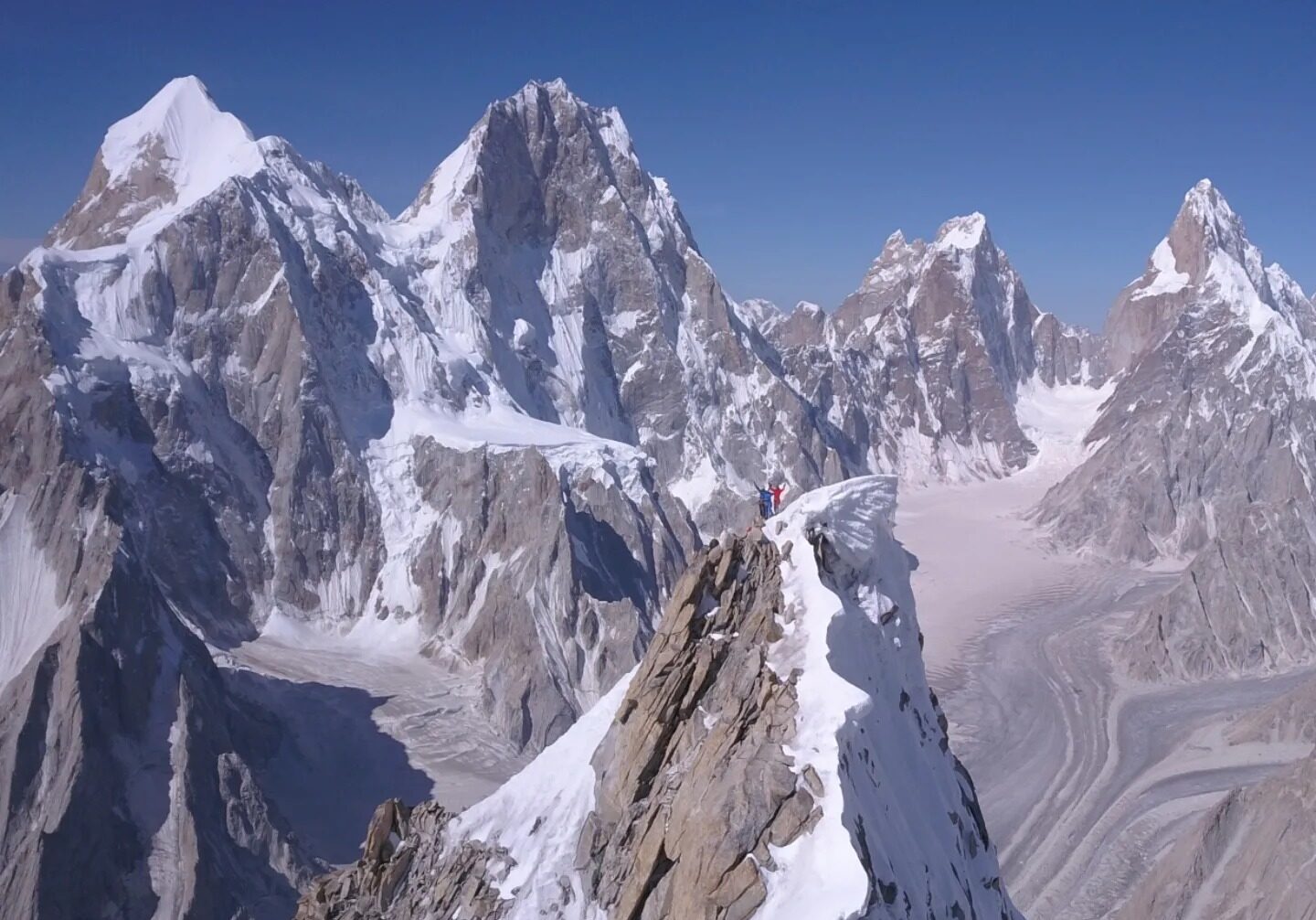 The climber on a peaky summit with other sharp peaks around.