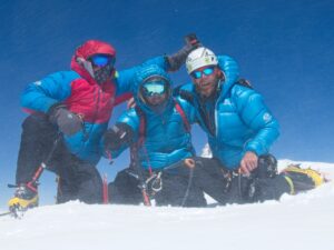 The climbers on a sunny but windy summit, totally covered in snow