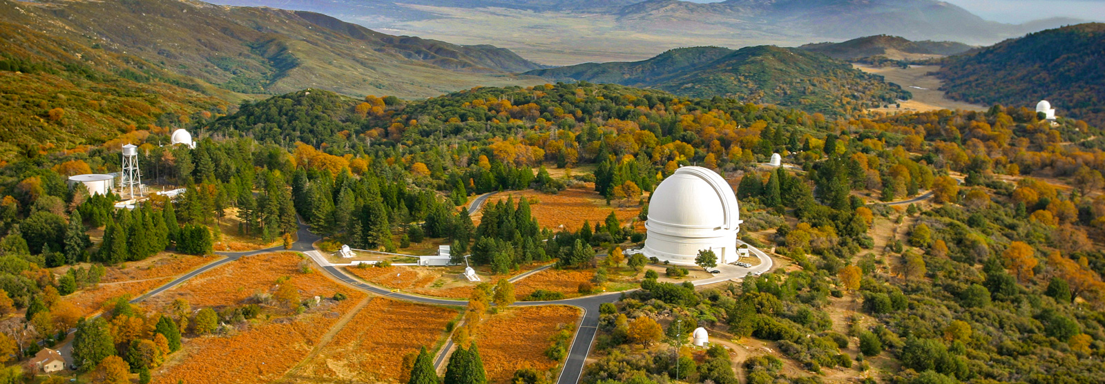 An aerial shot of a collection of domed telescopes nestled in the mountains. 