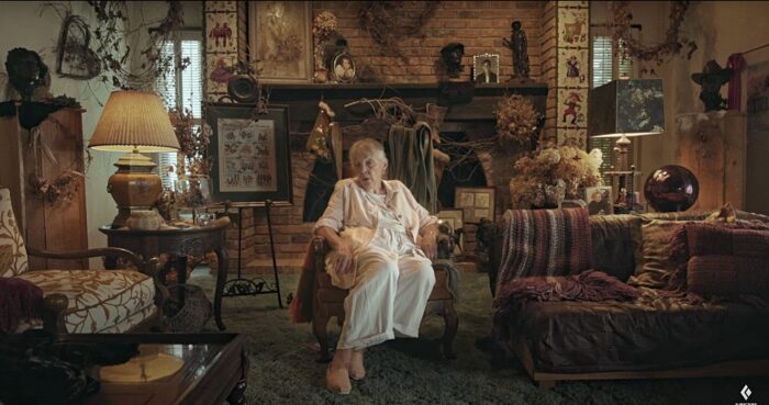 old woman in a white dress sitting in oddly decorated living room