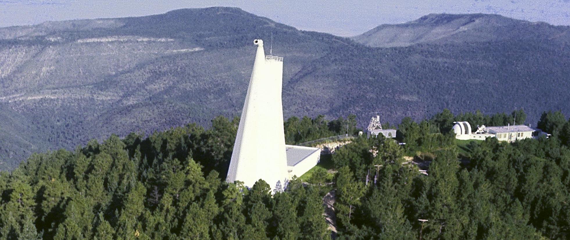 A funnel-shaped telescope sits on a mountain peak.