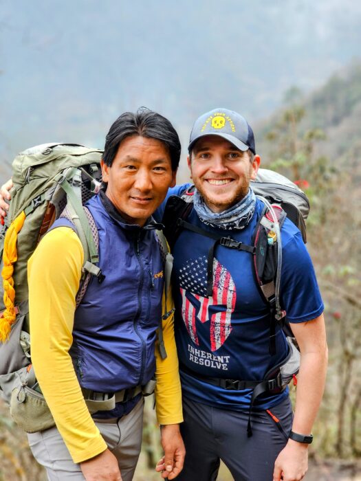 The two climbers stand side by side in trekking clothes and with backpacks on