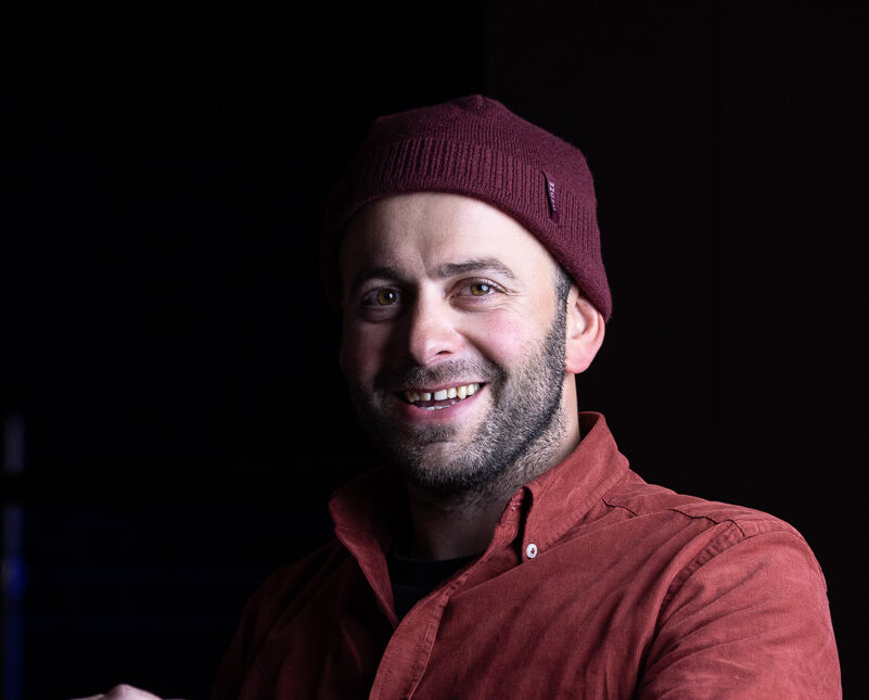 Close shot of Archil with a woolen beanie and black background.