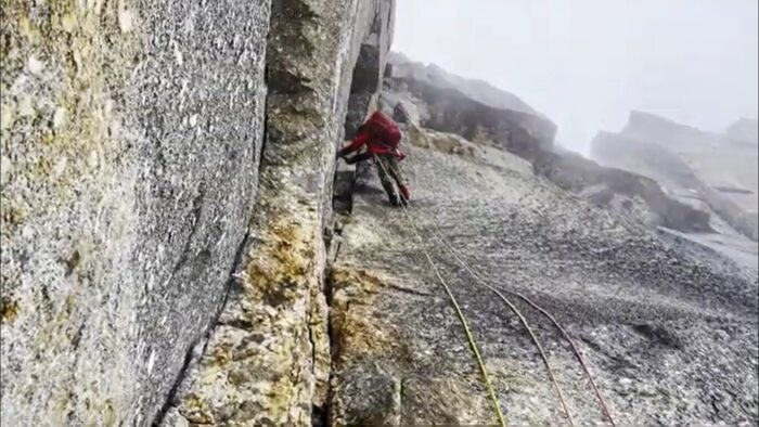 A climber on a granite dihedral in the fog.