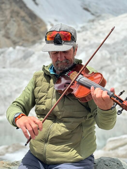 The climber playing the violin with a glacier behind him