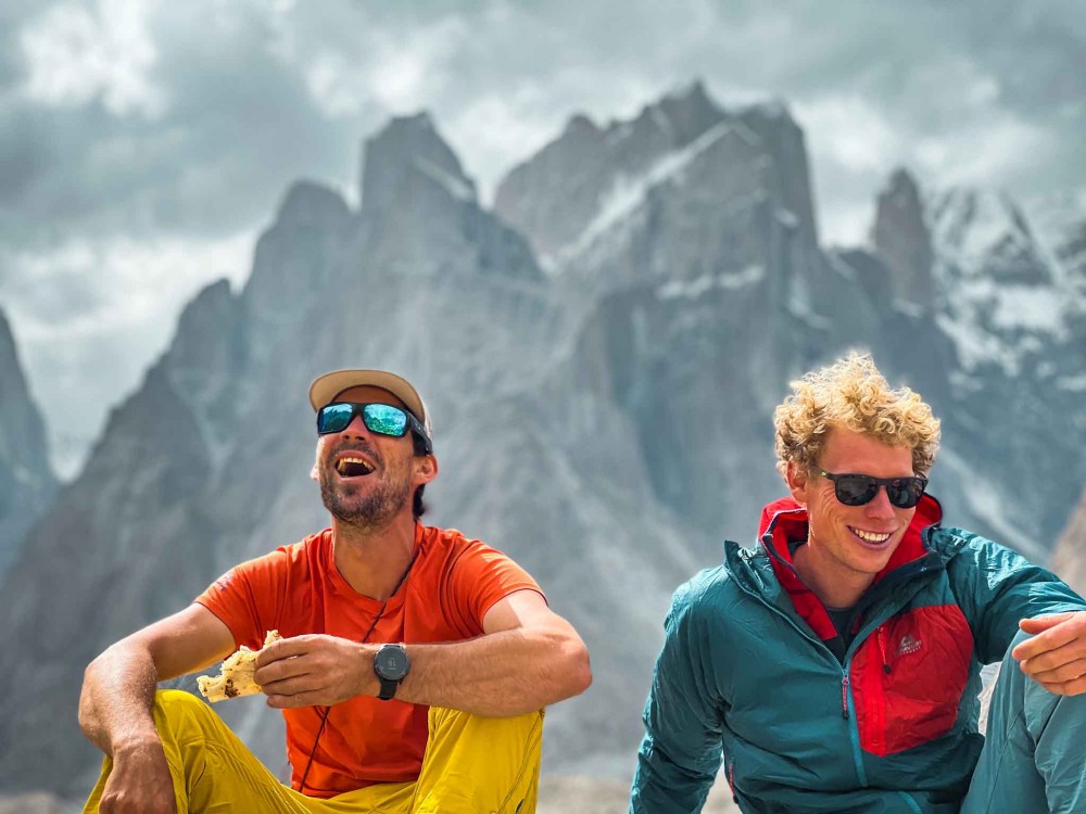 Cesen and Livingstone laugh while posing with ragged peaks behind them.