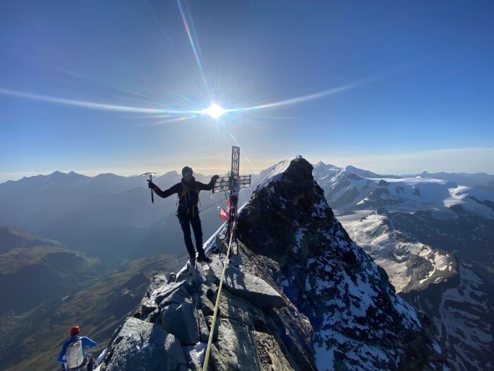 a climber clings to the iron cross installed on the summit of Matterhorn.