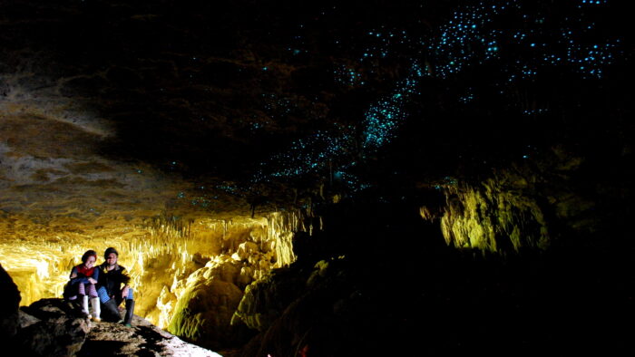 two people sit in a cavern with glowworms on the roof