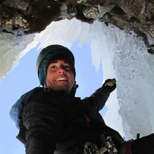 Portrait of Hennessey in a rock overhanging section surrounded by icicles