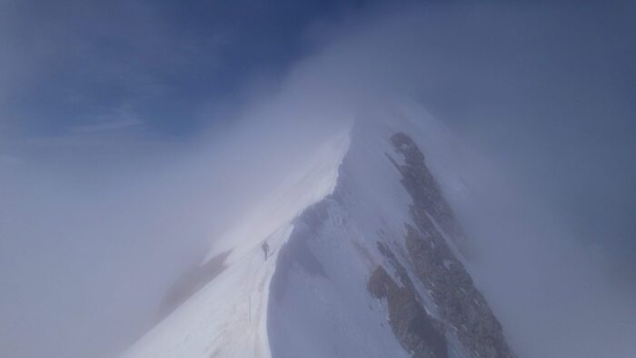 Jornet on a sharp, snow-covered ridge, on a foggy day