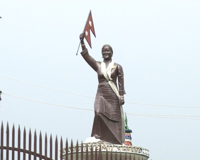 Statue of the Sherpa woman Pasang Lhamu, holding a Nepal flag and with a white khata scarf around her neck.