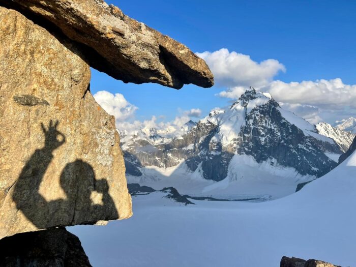 The shadow of the climber on a granite slab, peaks in background