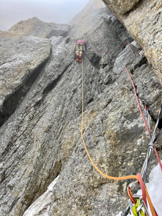 A climber on a granite wall in a foggy day, as seen from the belay