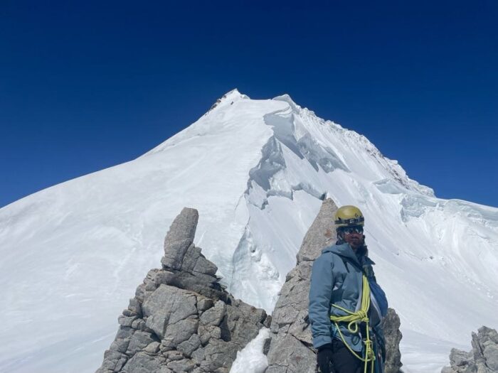 A climber on a saddle, the peak behind him