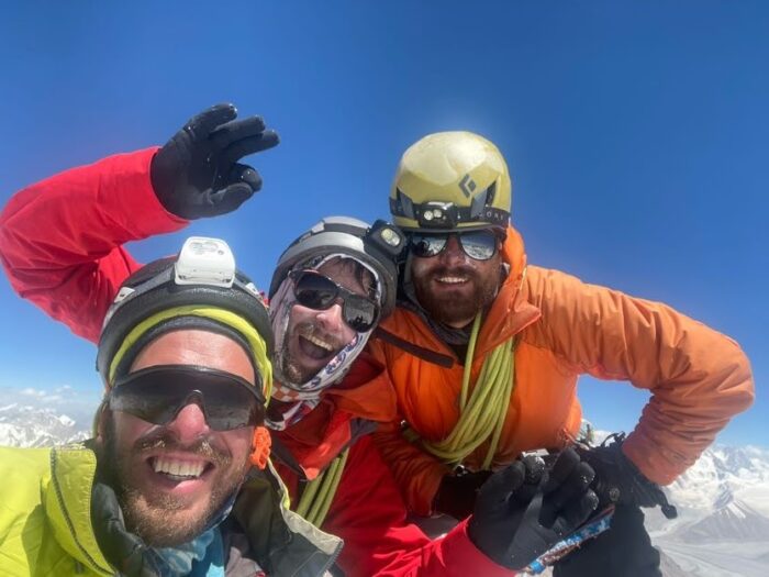 climbers smile on a summit in a sunny day