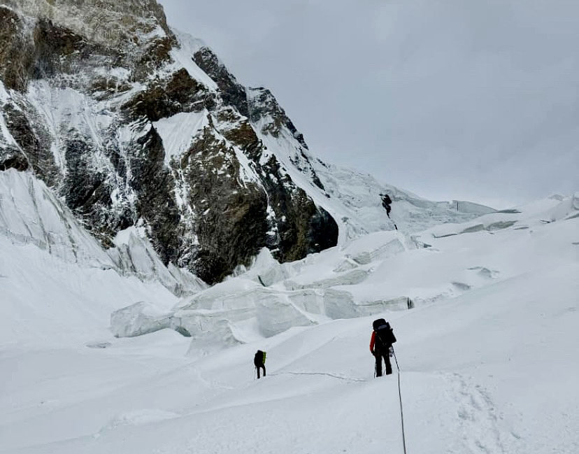 three climbers in snow near rocky outcrop