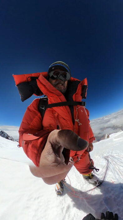 the climber takes a selfie while standing on the summit of K2