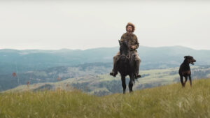 a man rides a horse with mountains in the background