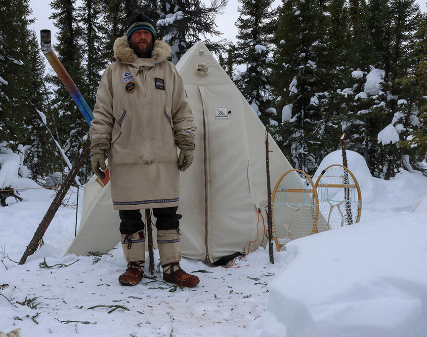 man outside bush tent in the woods