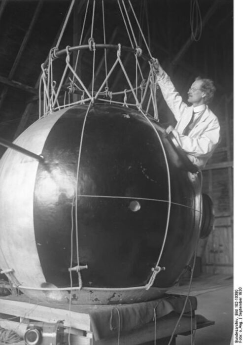 a scientist stands next to a black and white sphere