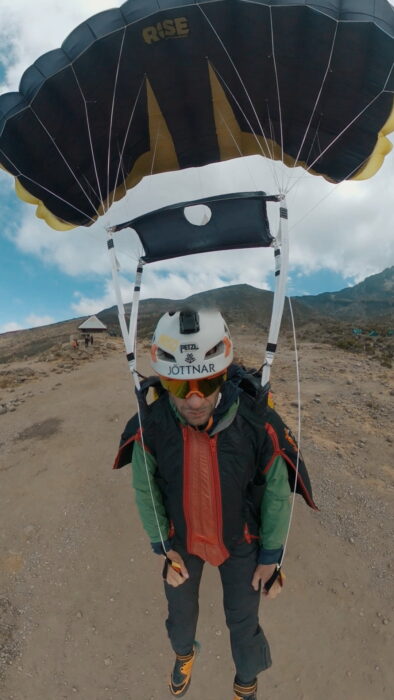 The wingsuit pilot with the parachute open right before landing