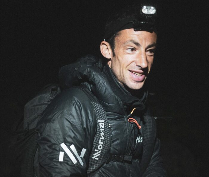 Close shot of Kilian Jornet with a headlamp, back background