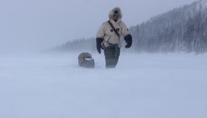 man snowshoeing on stormy lake