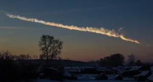 A trail of smoke cuts through the early morning sky. A tree stands on the horizon.