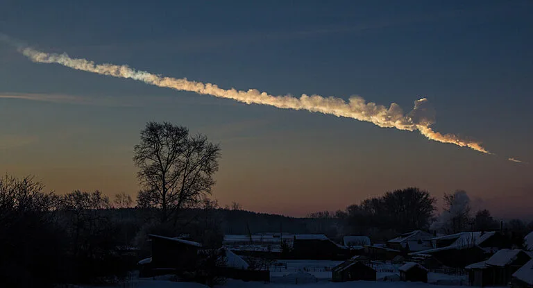 A trail of smoke cuts through the early morning sky. A tree stands on the horizon.