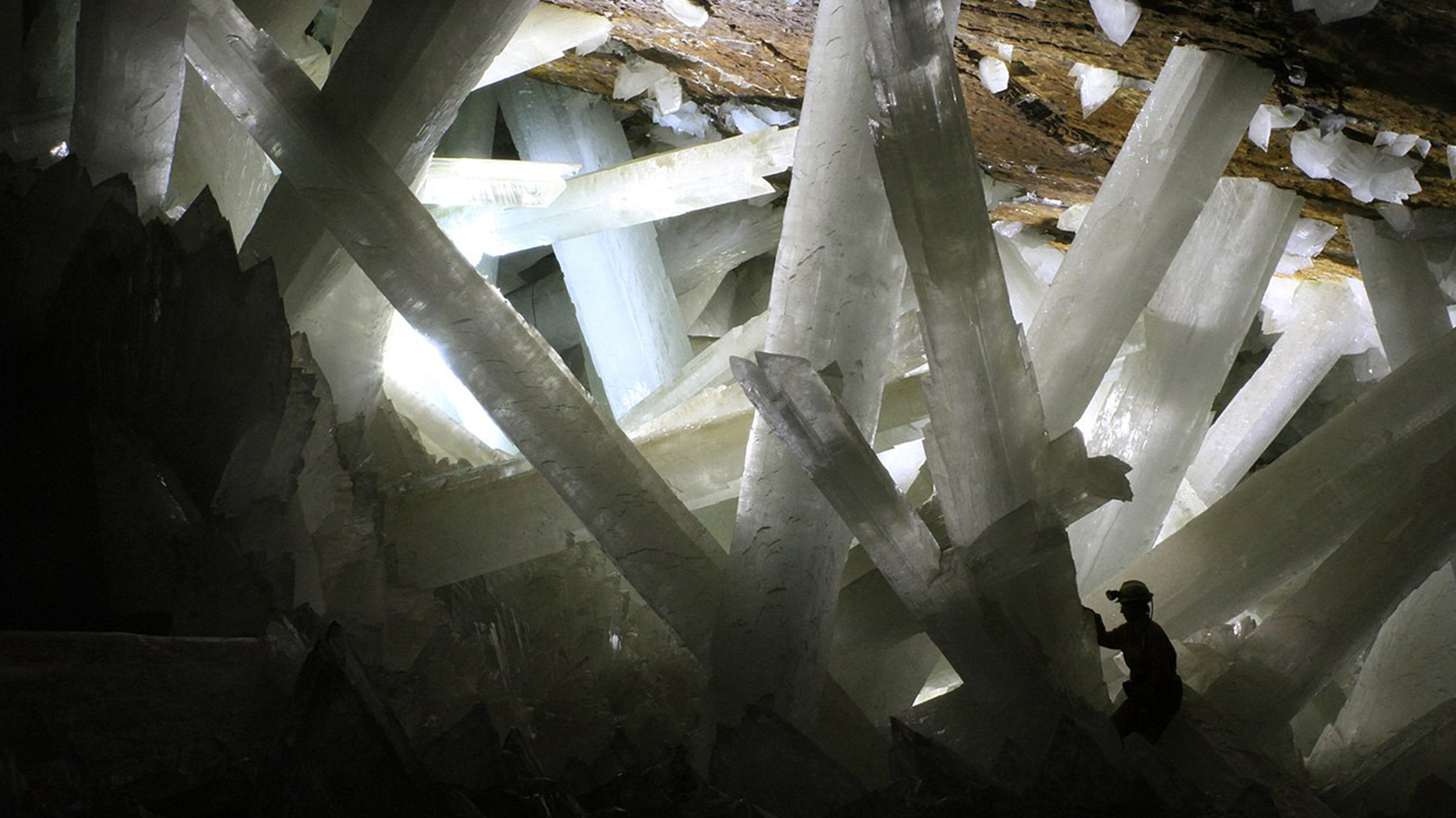 a small figure explores a huge cave of crystals