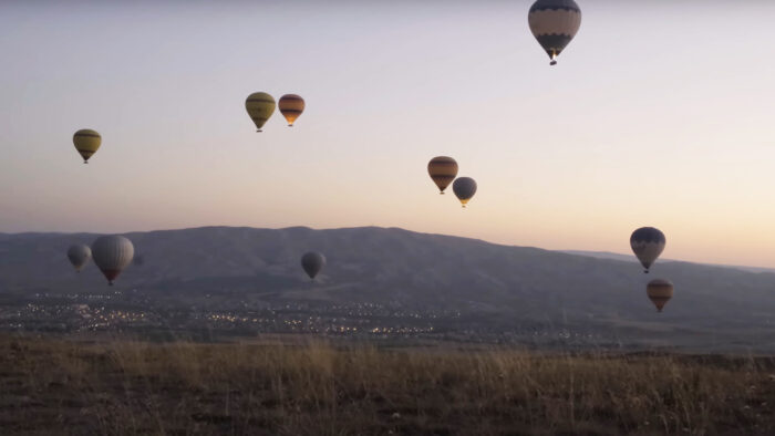 hot air balloons with low, brown mountains in the distance