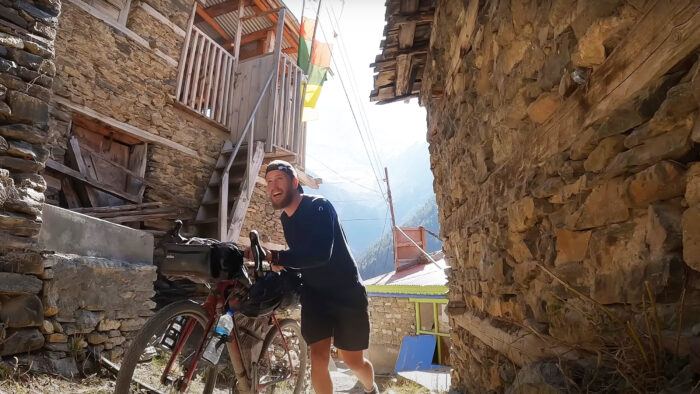 a man pushes his bike through a Nepalese village