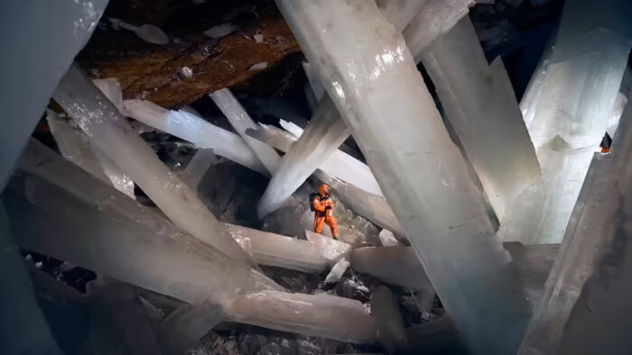 a small figure explores huge crystals