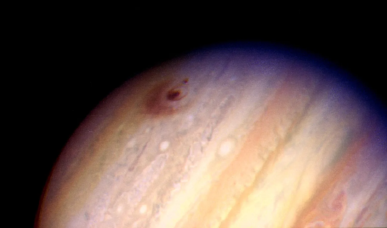 An image of Jupiter showing a large brown ejecta region at the top.