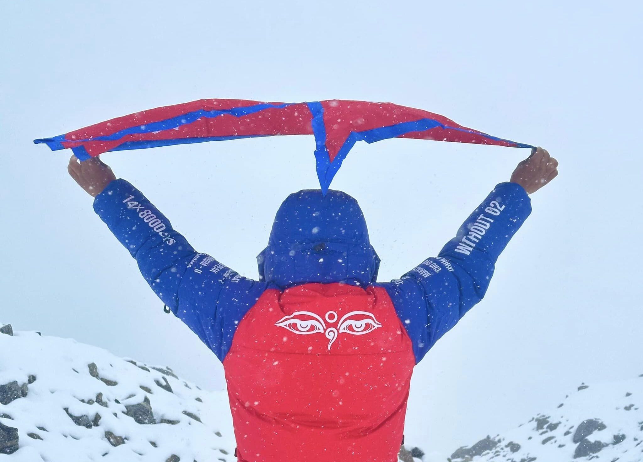 The Sherpa climber holds a Nepali banner and shows the expedition logo and no.o2 note on his back.