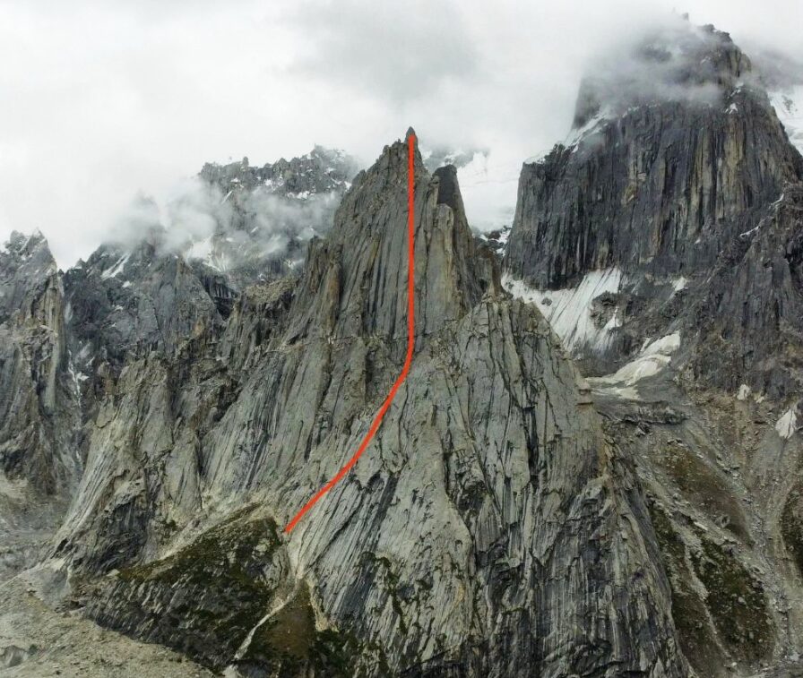 Route topo marked in red on the photo of a granite spire in a foggy day