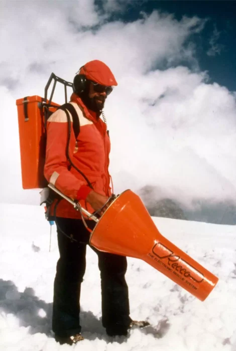 man holding a huge orange implement in snow