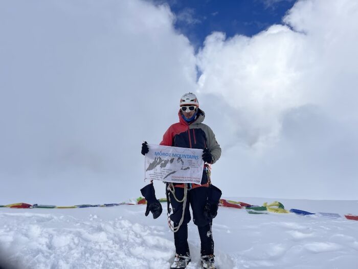 a climber of the flat summit of Ama dablam, holding a banner