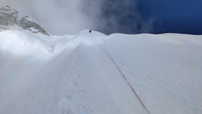 A snow ramp, a climber up on top of the rope. 