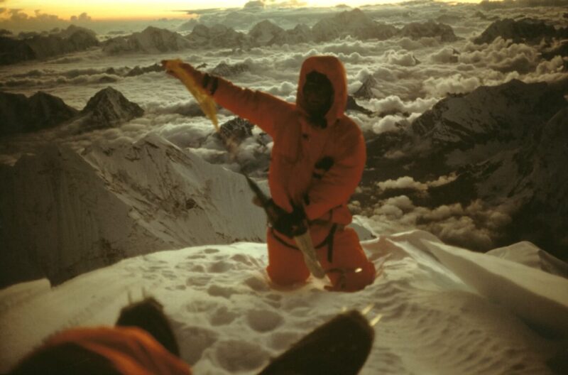 Greg Mortimer kneeling on the summit of Everest.