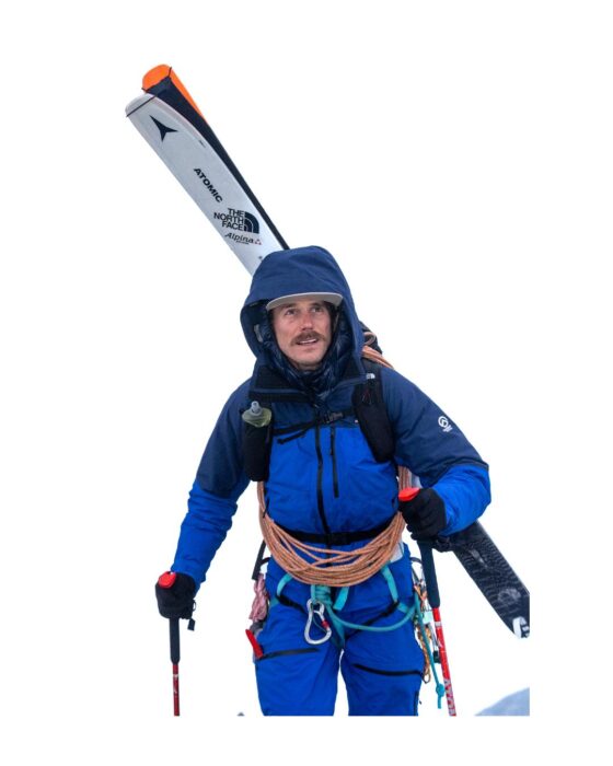 Guillaume Pierrel with his skis on his back in the snow