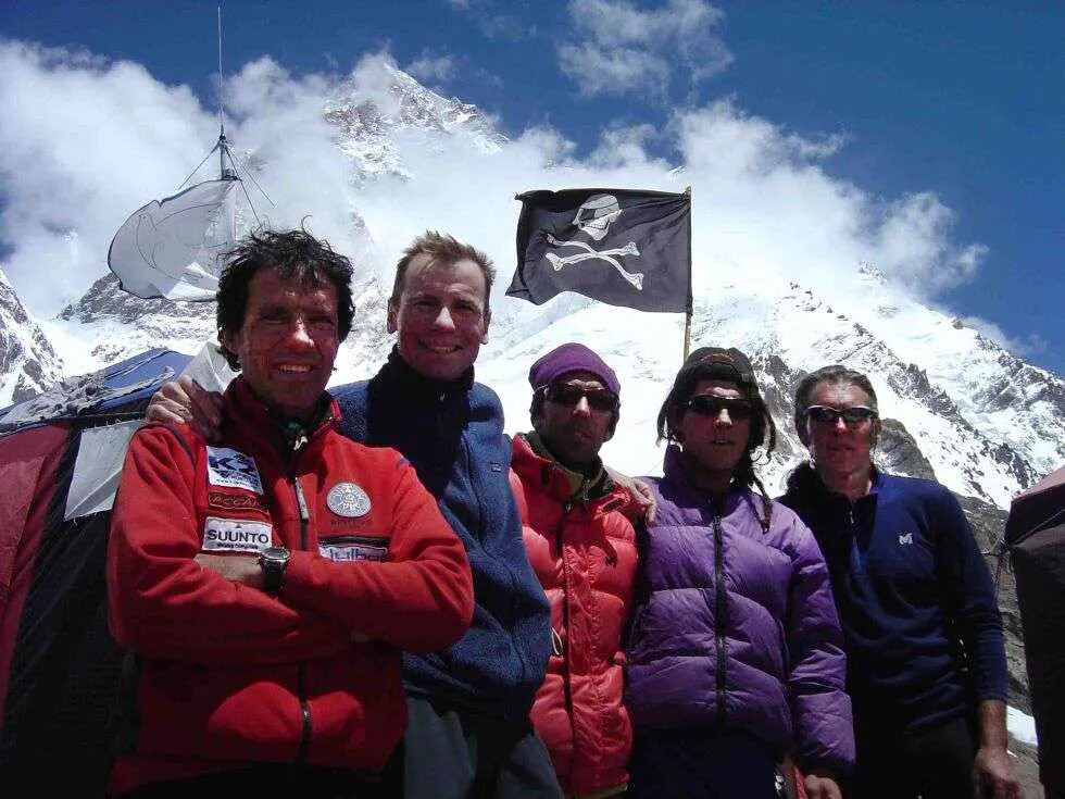 The climbers pose in Base Camp with the Jolly Roger flag and K2 in background