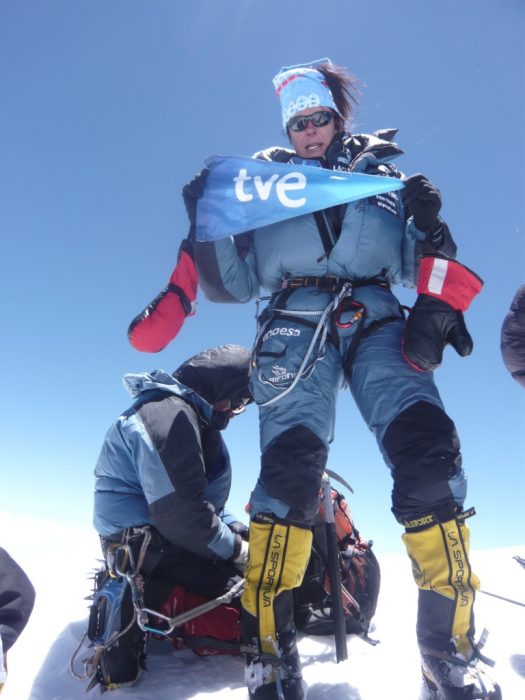 Pasaban stands on the summit holding a flag