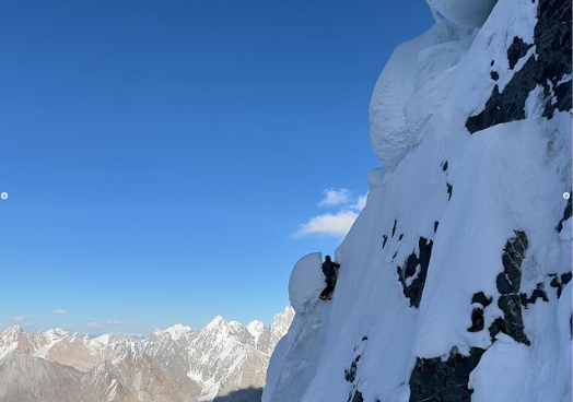 The climber on a meringue-like snow formations covering a steep buttress.