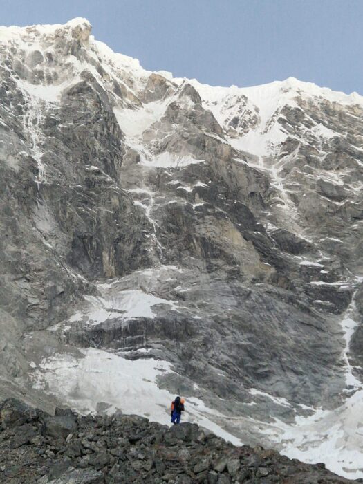 A climber looks tiny in front of the mighty East face of Langtang Lirung