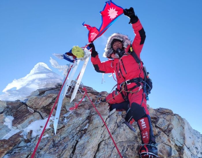 Tenjen Lama raises a Nepali flag on the summit of Manaslu, totally on rock in winter