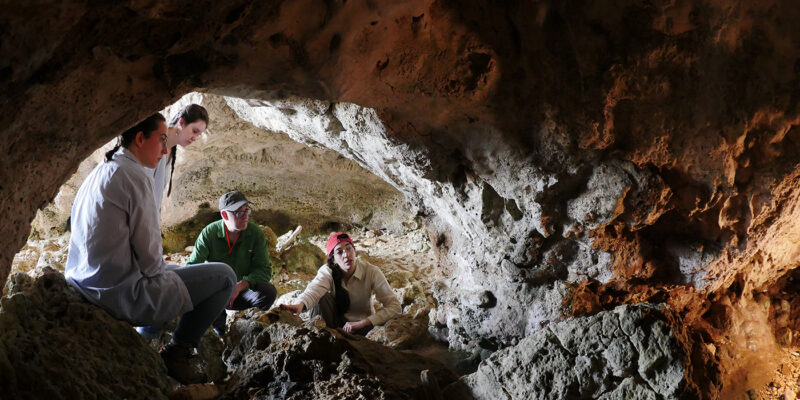 researchers huddled around cave entrance