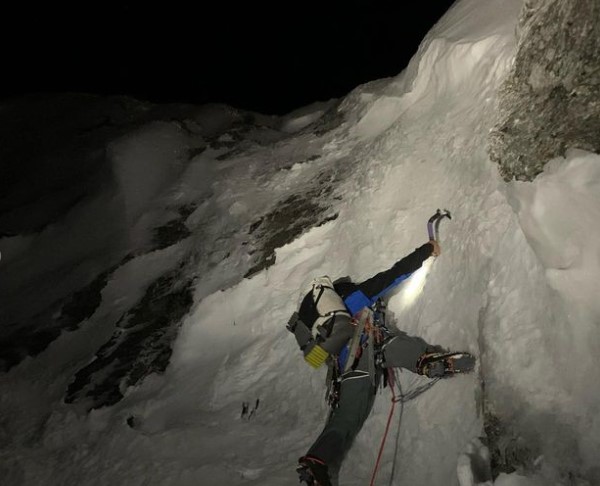 a climber on a vertical mixed wall, in the night.