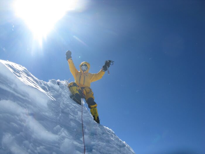 Moro raises his arms on a spiked snow summit