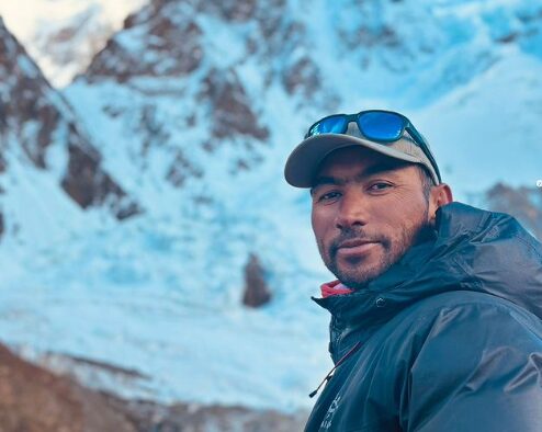 Sirbaz Khan with a baseball cap and the flanks of K2 behind him